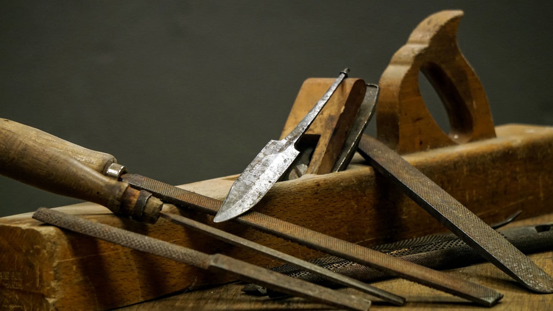 A detailed close-up of vintage carpentry tools and files arranged on a wooden plank.